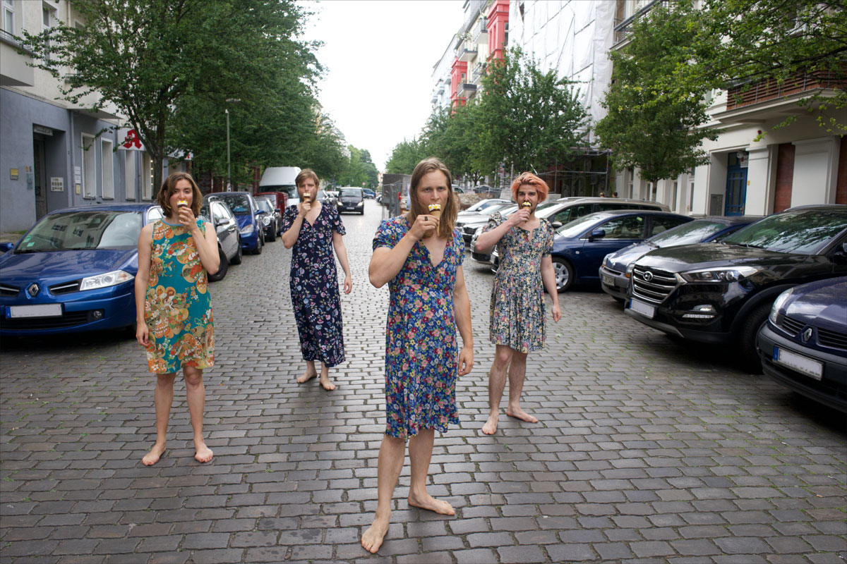 4 Männer barfuß auf der Kopfsteinpflasterstraße in petite fleur Kleidern essen Eis