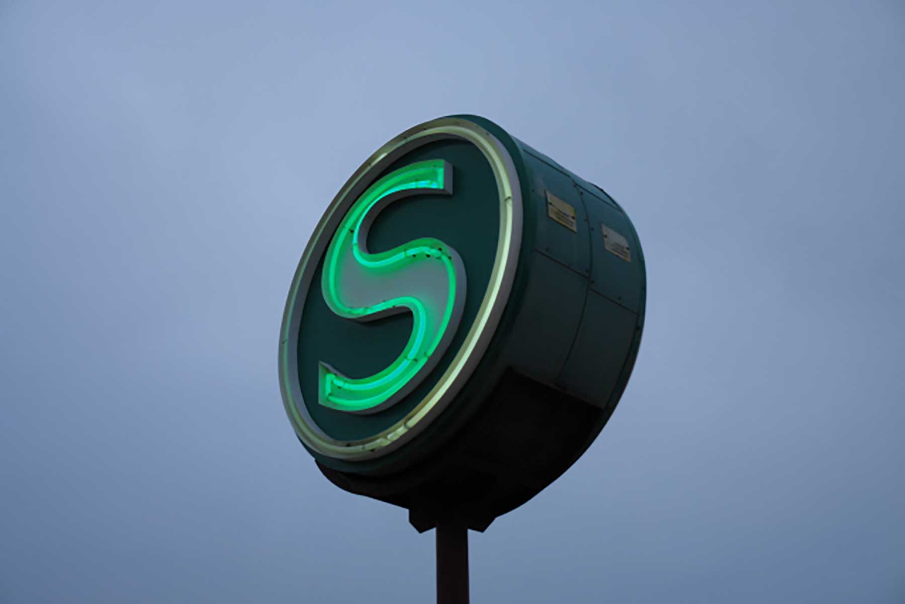 Das grüne Zeichen der Berliner S-Bahn vorm dämmernden Abendhimmel